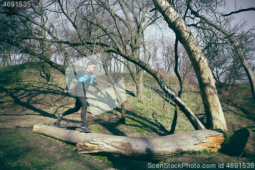 Image of Man running in a park or forest against trees background.