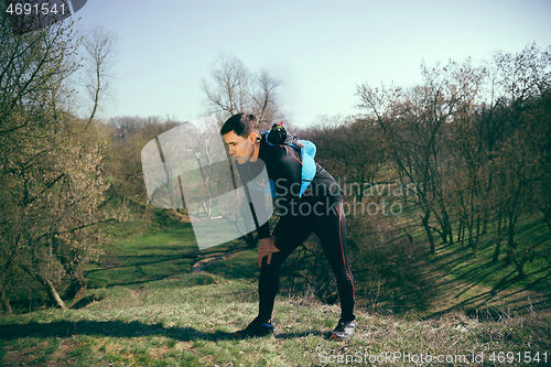 Image of Man after running in a park or forest against trees background.