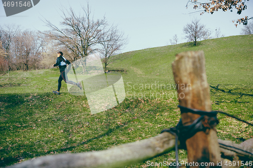 Image of Man running in a park or forest against trees background.