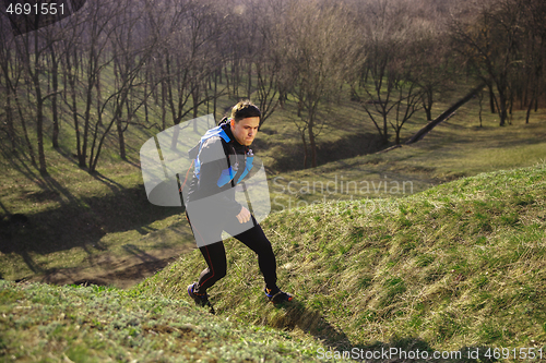 Image of Man running in a park or forest against trees background.