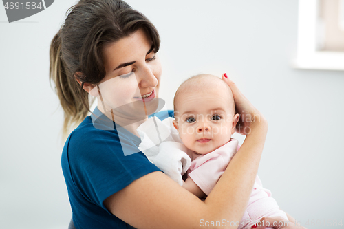 Image of mother holding baby daughter at home