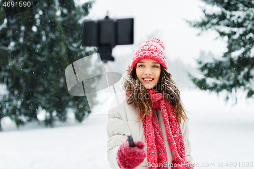 Image of young woman taking selfie by monopod in winter