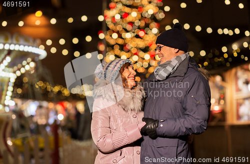 Image of happy senior couple hugging at christmas market