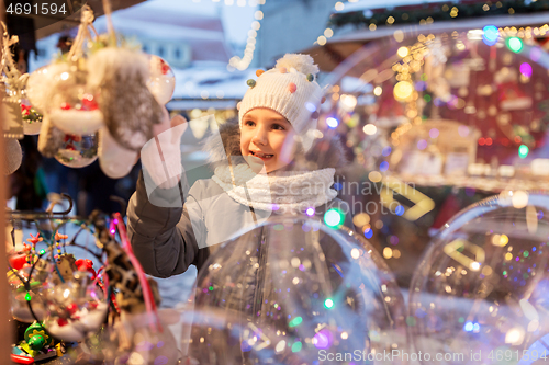 Image of little girl choosing christmas balls at market