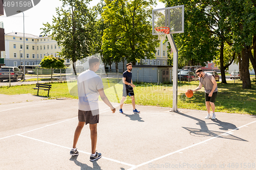 Image of group of male friends playing street basketball