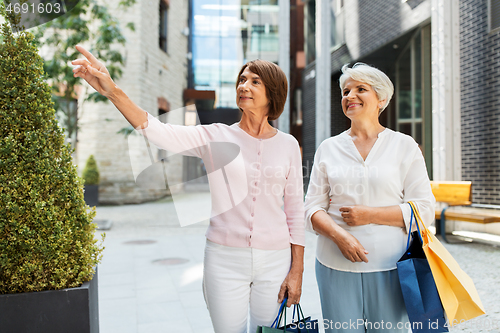 Image of senior women with shopping bags walking in city