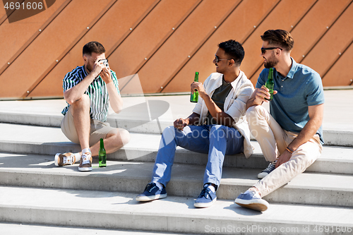 Image of man photographing friends drinking beer on street