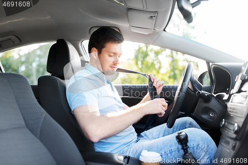 Image of man or car driver fastening seat belt