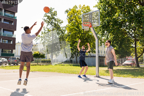 Image of group of male friends playing street basketball