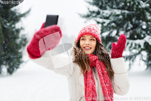 Image of young woman taking selfie by smartphone in winter