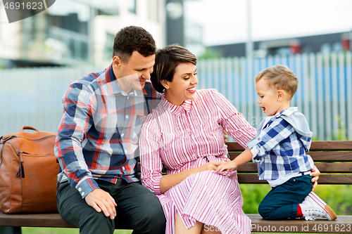 Image of happy family sitting on street bench in city