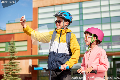 Image of happy school kids with scooters taking selfie