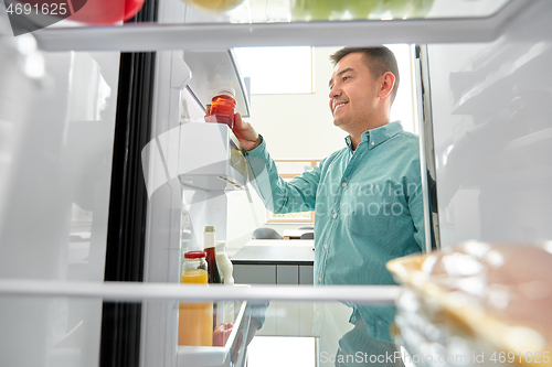Image of man taking juice from fridge at home kitchen