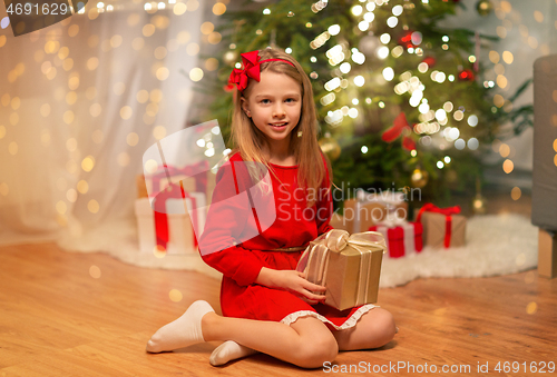 Image of smiling girl with christmas gift at home