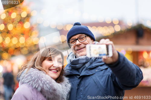 Image of senior couple taking selfie at christmas market