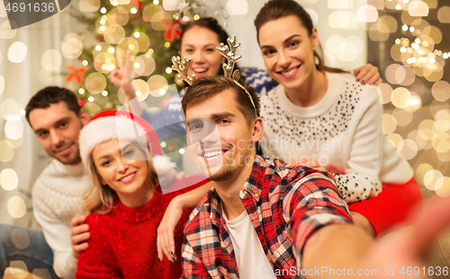 Image of friends celebrating christmas and taking selfie