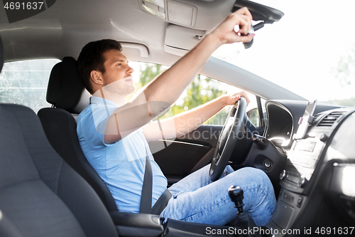 Image of man or car driver adjusting mirror