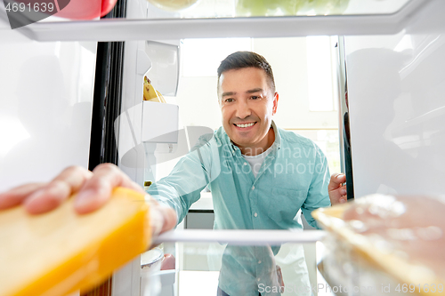 Image of man taking food from fridge at kitchen