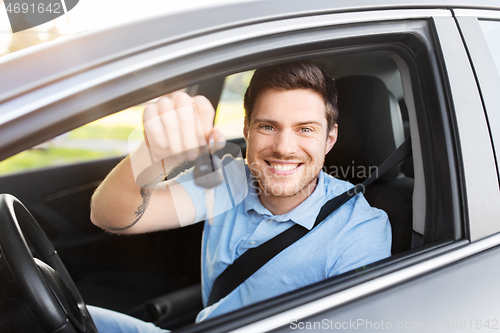 Image of smiling man or driver with key sitting in car