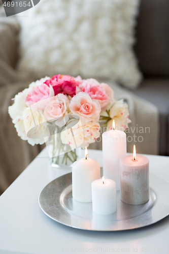 Image of candles burning on table and flowers at cozy home