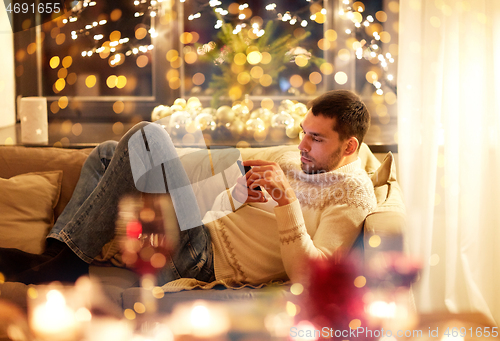 Image of man with smartphone at home at christmas eve