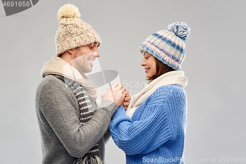 Image of happy couple in winter clothes holding hands
