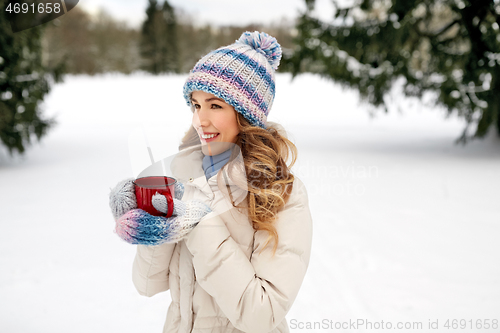 Image of happy young woman with tea cup outdoors in winter