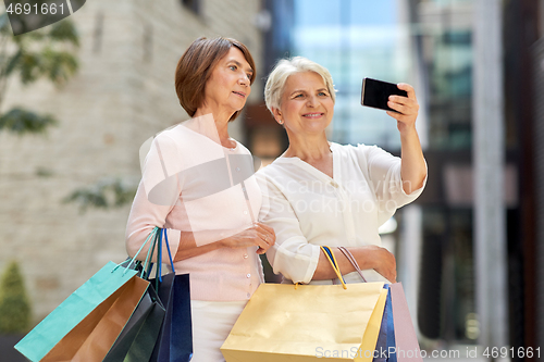 Image of old women with shopping bags taking selfie in city