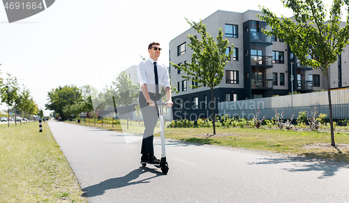 Image of young businessman riding electric scooter outdoors