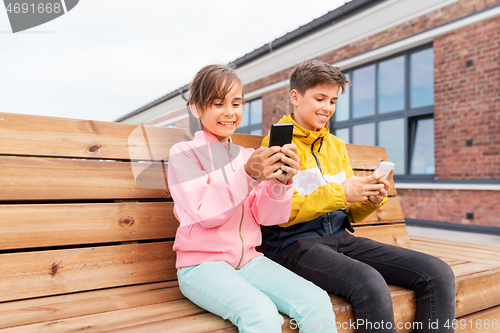 Image of children with smartphones sitting on street bench