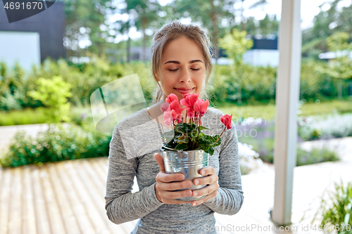 Image of young woman with cyclamen flowers at summer garden
