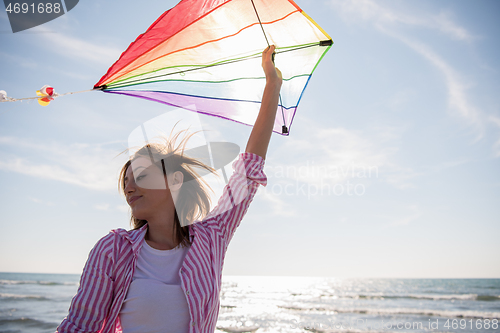 Image of Young Woman with kite at beach on autumn day