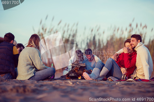 Image of Couple enjoying with friends at sunset on the beach