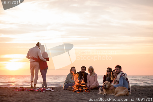 Image of Couple enjoying with friends at sunset on the beach