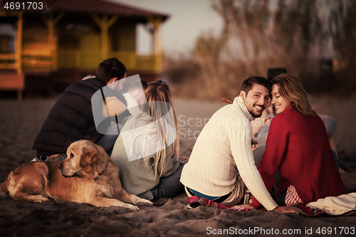 Image of Couple enjoying with friends at sunset on the beach