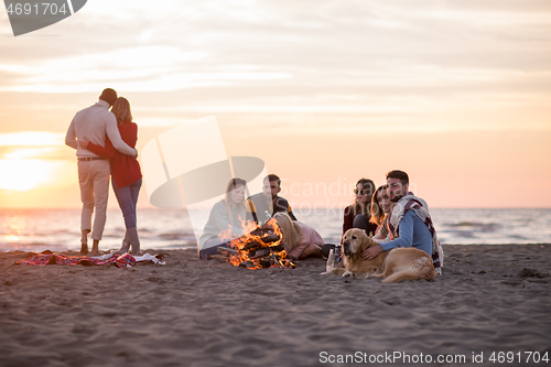 Image of Couple enjoying with friends at sunset on the beach