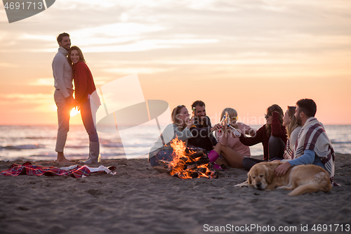 Image of Couple enjoying with friends at sunset on the beach