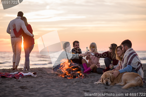 Image of Couple enjoying with friends at sunset on the beach