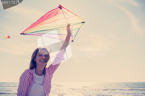 Image of Young Woman with kite at beach on autumn day