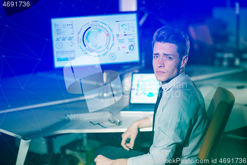 Image of man working on computer in dark office