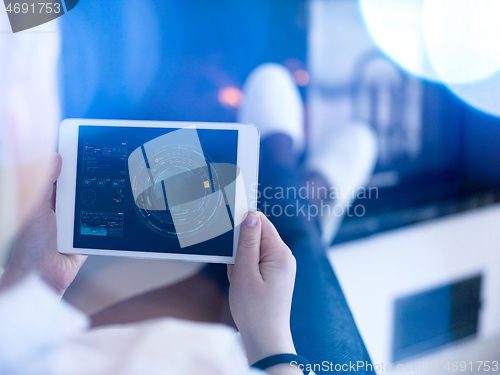 Image of young woman using tablet computer in front of fireplace