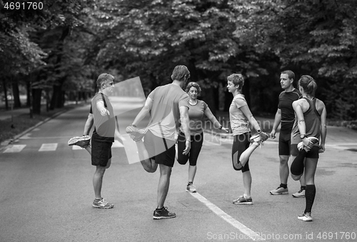 Image of runners team warming up and stretching before morning training