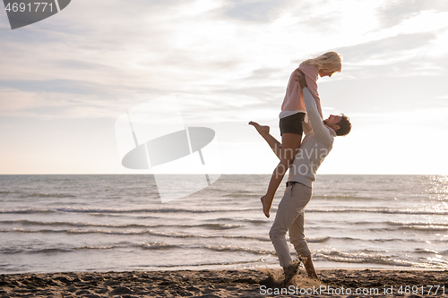 Image of Loving young couple on a beach at autumn sunny day