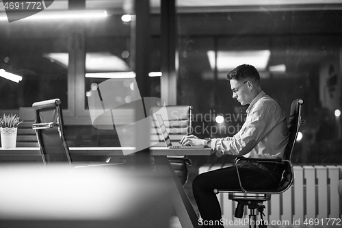 Image of man working on laptop in dark office