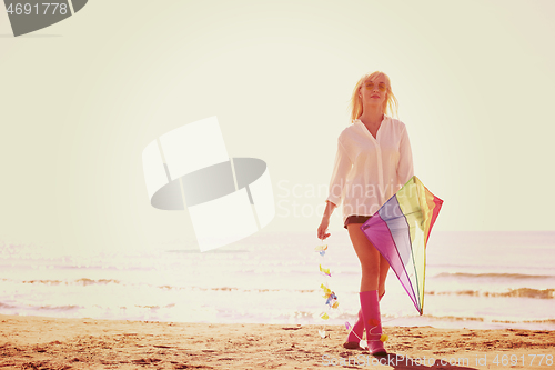 Image of Young Woman with kite at beach on autumn day