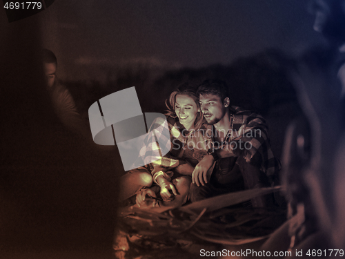 Image of Couple enjoying with friends at night on the beach