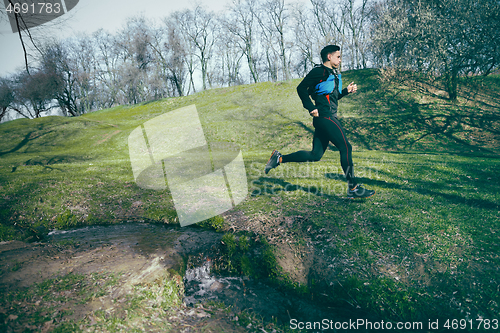 Image of Man running in a park or forest against trees background.