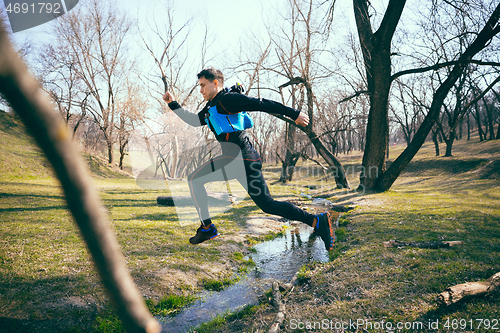 Image of Man running in a park or forest against trees background.