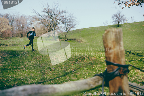 Image of Man running in a park or forest against trees background.