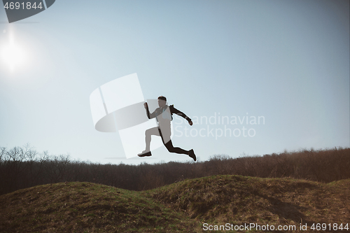 Image of Man running in a park or forest against trees background.
